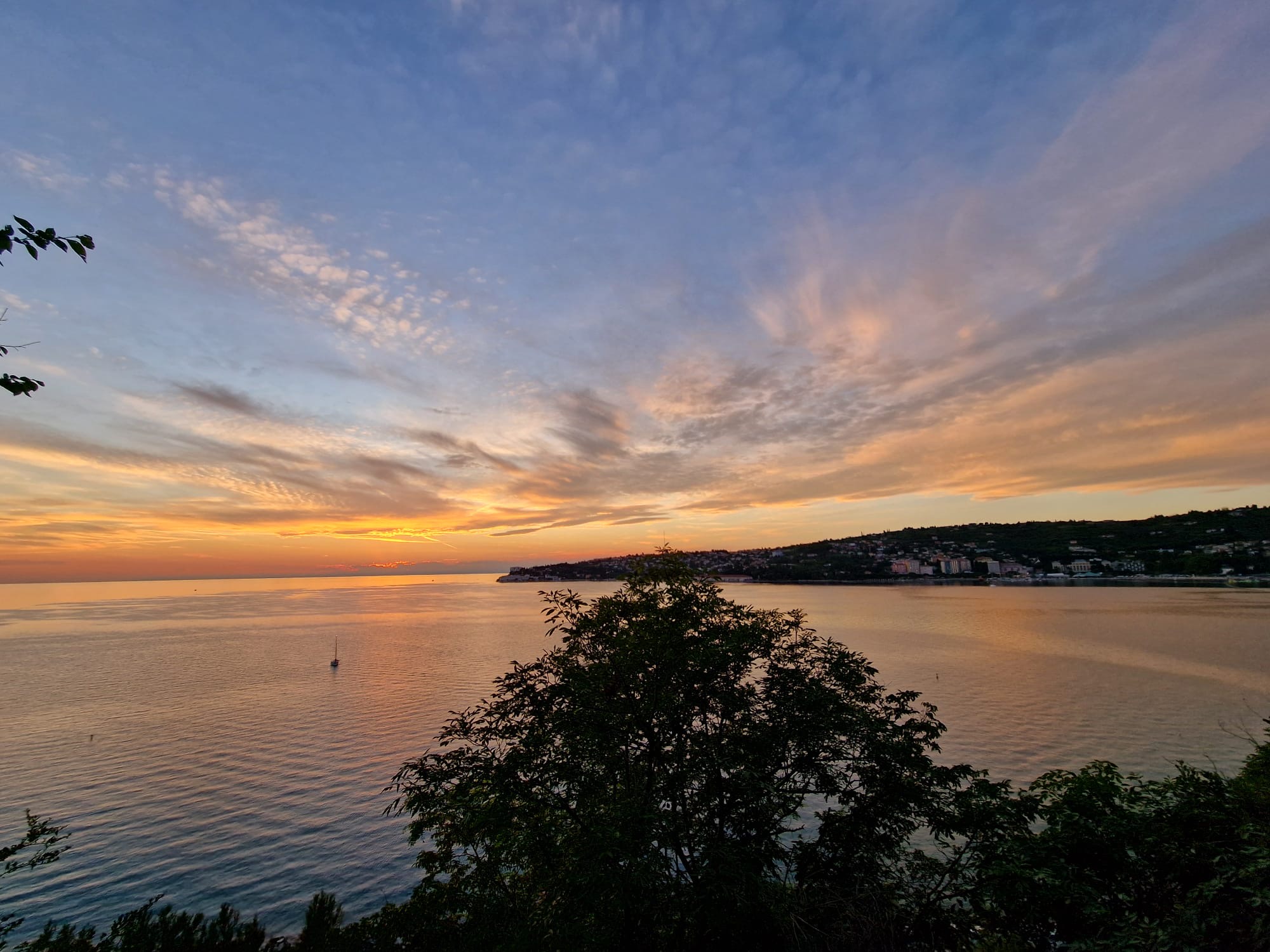 Sunset over the Adriatic sea near Portorož with a sailboat on calm golden water